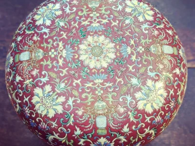 Round maroon ball with intricate blue, cream and green floral and scroll patterns, lantern motifs and central medallion.