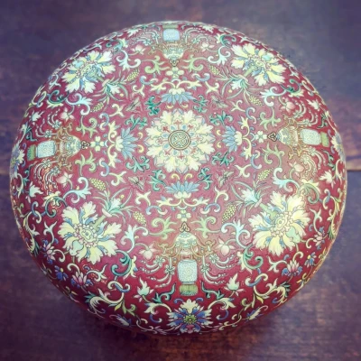 Round maroon ball with intricate blue, cream and green floral and scroll patterns, lantern motifs and central medallion.
