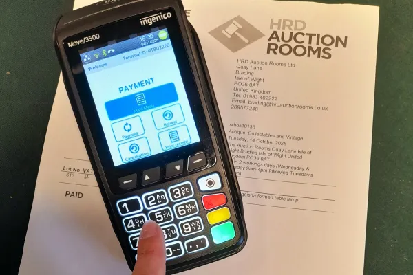 Ingenico Move/3500 payment terminal on a printed HRD Auction Rooms document; screen shows Payment Main Menu with a finger on the keypad.